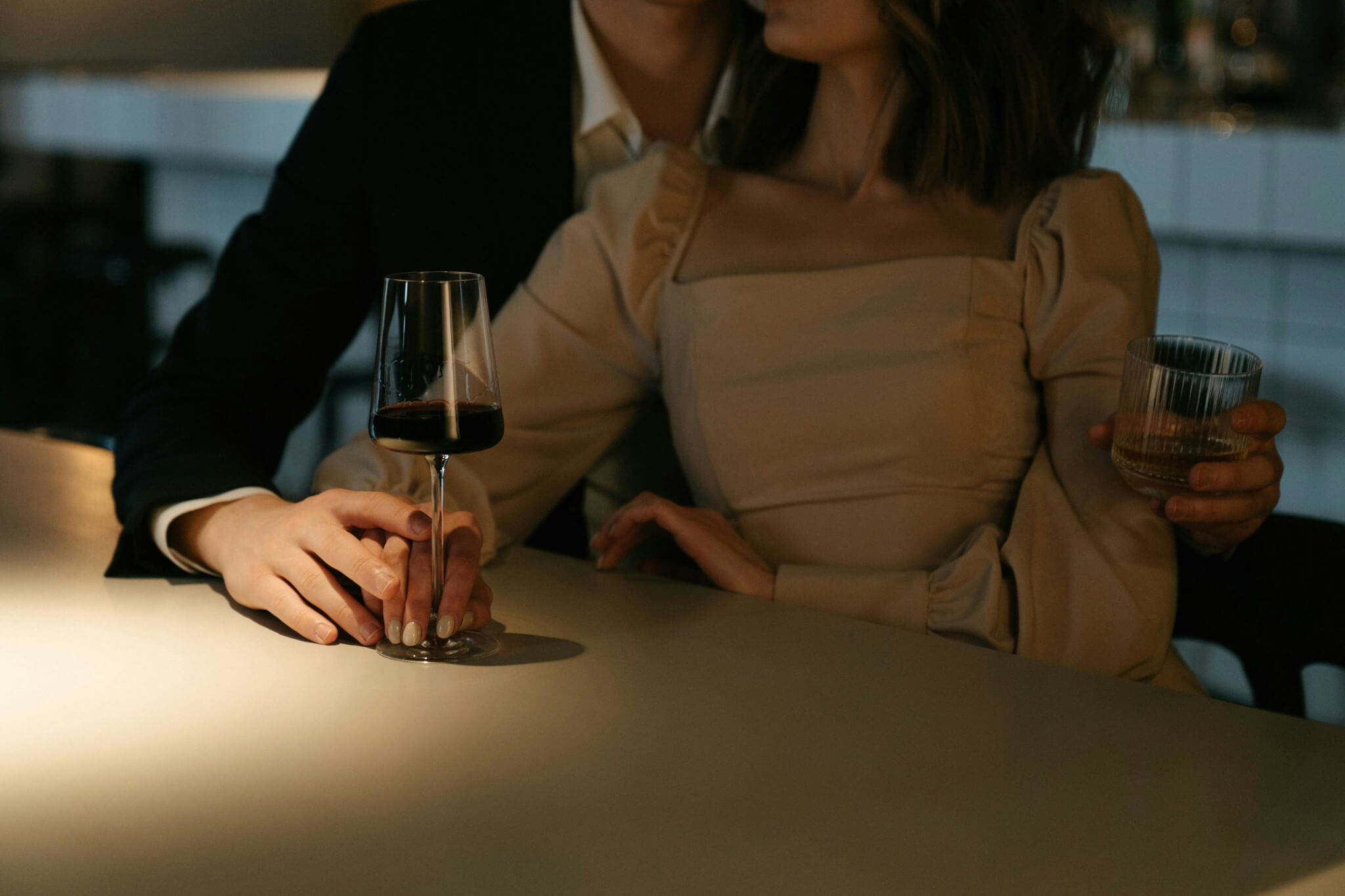 A romantic couple sharing a glass of red wine by candlelight at Theodosia Restaurant, wrapped in a soft, intimate glow.