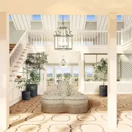Homepage 22 Lobby of The Sanderling Resort with a central sofa, plants, and a large central chandelier, filled with natural light.