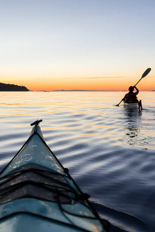 Homepage 11 Two people kayaking at sunset near The Sanderling Hotel, enjoying a peaceful coastal adventure