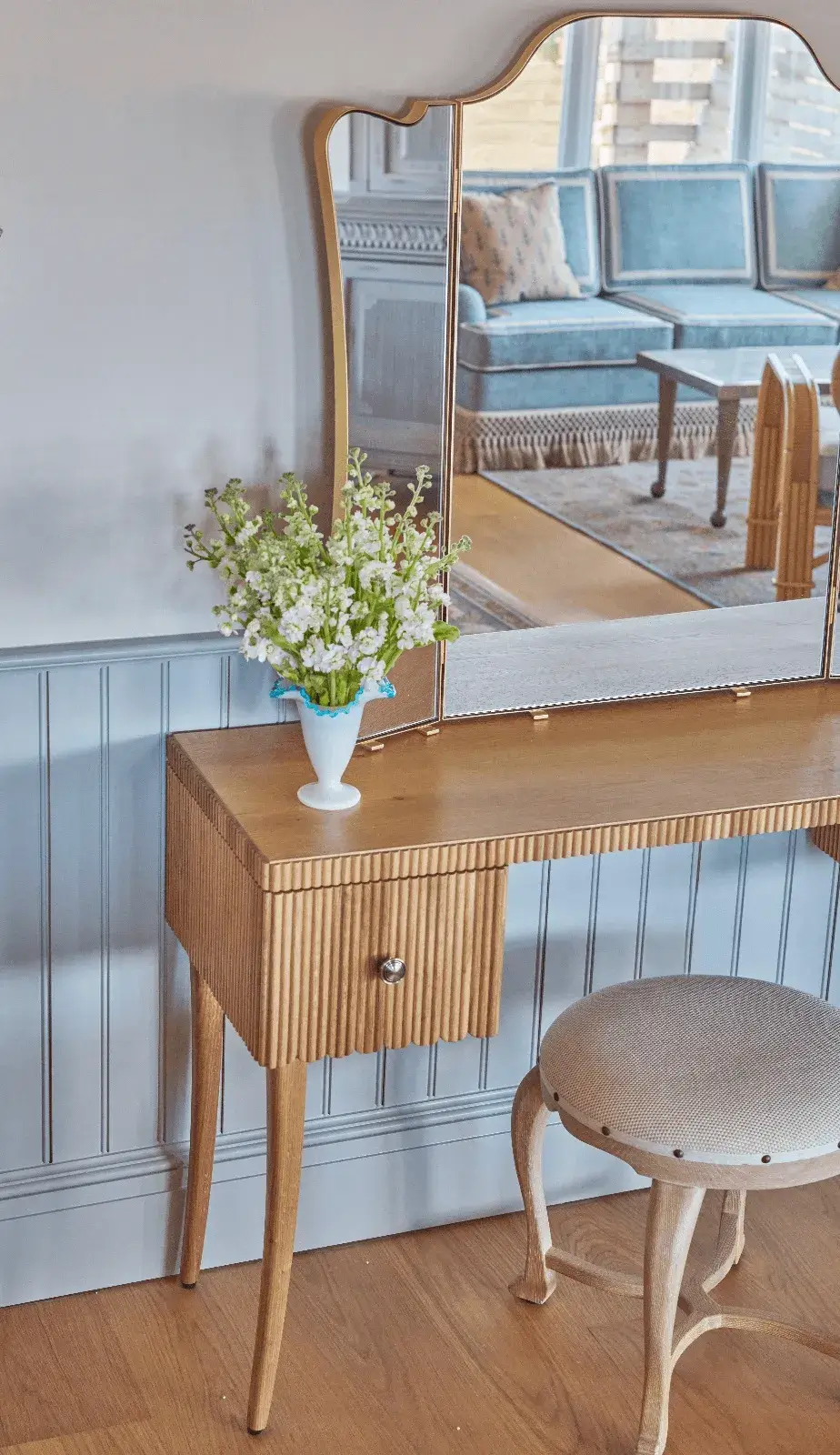 Beautiful wooden sideboard with a gold-framed mirror and fresh flowers.