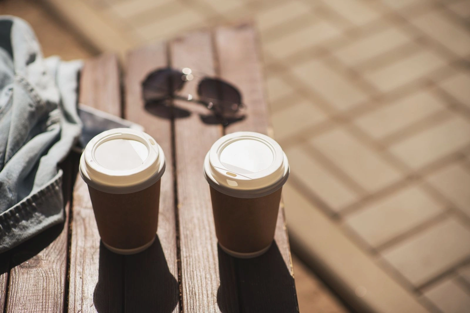 UOvgzyJM Two to-go coffee cups resting on a wooden bench, ready for a cozy stroll.